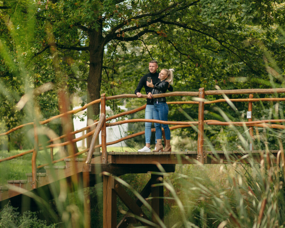 Das Bild zeigt ein Pärchen auf einer kleinen Holzbrücke im Georgium in Dessau, die ein Bild von sich machen